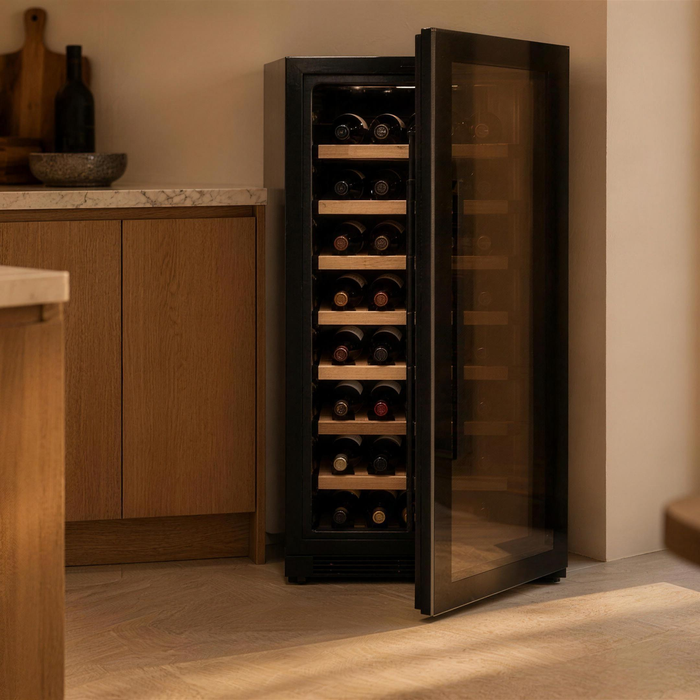 Vrijstaande wijnkoelkast met geopende glasdeur en liggende wijnflessen in een warme houten keuken